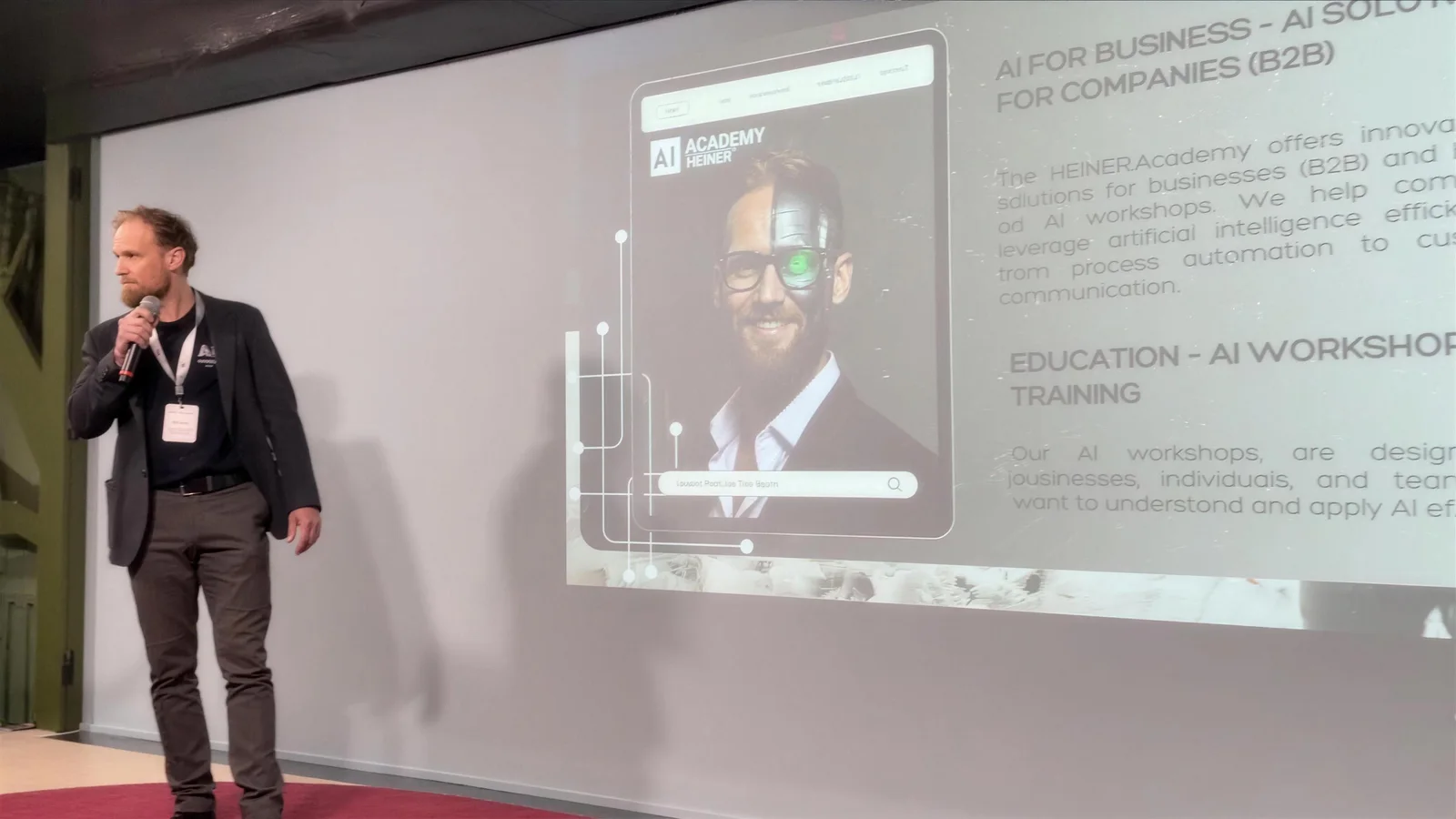 André Heiner hält einen KI-Vortrag mit Mikrofon vor einer Präsentation zu AI Workshops und KI-Weiterbildung der HEINER Academy